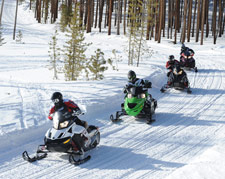 Snowmobilers enjoying their sleds along a groomed path